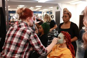 Students applying makeup to model dressed as Sally